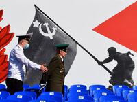 A police officer assists a veteran prior to a military parade, which marks the 75th anniversary of the Soviet victory over Nazi Germany in World War Two, at Dvortsovaya Square in Saint Petersburg on June 24, 2020. The parade, usually held on May 9, was postponed this year because of the coronavirus pandemic. OLGA MALTSEVA / AFP
