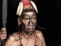 A shirtless tribesman warrior is pictured wearing a traditional headdress and brandishing a spear with a heavily tattooed chest.  (Mediadrumimages/ Trevor Cole)