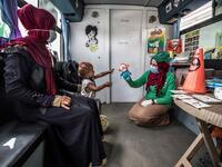 A woman looks on as a worker entertains a homeless child inside one of the mobile units run by the Egyptian authorities and used as part of the "Atfal bala ma'wa" (Children without a home) social program, in the capital Cairo's Abbasia district on June 22, 2020. Khaled DESOUKI / AFP