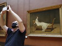 A woman wearing face mask takes a pictures as she visit the Louvre Museum in Paris on July 6, 2020, on the museum' s reopening day. FRANCOIS GUILLOT / AFP