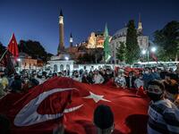 People, some wearing face masks, wave a giant Turkey national flag and shout slogans outside the Hagia Sophia museum in Istanbul on July 10, 2020 as they gather to celebrate after a top Turkish court revoked the sixth-century Hagia Sophia's status as a museum, clearing the way for it to be turned back into a mosque. The Council of State, the country's highest administrative court which on July 2 debated a case brought by a Turkish NGO, cancelled a 1934 cabinet decision and ruled the UNESCO World Heritage si