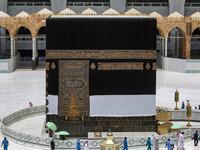 Workers at the Grand Mosque complex in Saudi Arabia's holy city of Mecca, mask-clad due to the COVID-19 coronavirus pandemic, wave and speak to a security guard as they walk around the Kaaba, Islam's holiest shrine, at centre of the complex ahead of the annual Hajj pilgrimage season on July 24, 2020. AFP