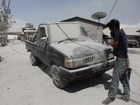 A man cleans a car covered with ash following an eruption by Mount Sinabung at the Sukatepu village in Karo, North Sumatra, on August 10, 2020. Ivan Damanik / AFP