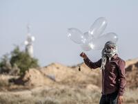 A Palestinian prepares to launch inflated condoms attached with an incendiary device to be directed and flown towards Israel, near Rafah along the border between the Gaza Strip and Israel on August 21, 2020. SAID KHATIB / AFP