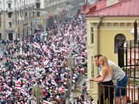 A couple looks at demonstrators from a balcony during a march of opposition supporters to protest against disputed presidential elections results in Minsk on August 23, 2020. Sergei GAPON / AFP
