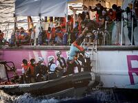 Crew members of civil sea rescue ship Sea-Watch 4 and medical Doctors Without Borders (MSF) on inflatable boats help migrants to get off the rescue ship (AFP)