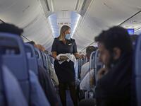 A flight attendant hands out chocolates with a greeting card to passengers on an El Al plane from Israel en route to Abu Dhabi, on August 31, 2020. A US-Israeli delegation including White House advisor Jared Kushner took off on a historic first direct commercial flight from Tel Aviv to Abu Dhabi to mark the normalisation of ties between the Jewish state and the UAE. NIR ELIAS / AFP
