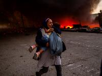 A migrant holds a girl as they flee a fire burning in the Moria camp on the island of Lesbos on September 9, 2020. Thousands of asylum seekers on the Greek island of Lesbos fled for their lives on September 9, 2020 as a huge fire ripped through the camp of Moria, the country's largest and most notorious migrant facility. 