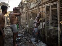 Migrants take shower Children walk in the burnt migrants camp of Moria on the Greek Aegean island of Lesbos on September 9, 2020 after a major fire broke out. Thousands of asylum seekers were left homeless on September 9 after a fire gutted Greece's largest migrant camp on Lesbos, plunging the island into crisis and provoking an outpouring of sympathy from around Europe and calls for reform of the refugee system. 