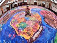 Contemporary British artist Sacha Jafri (C) stands on his record-breaking painting entitled 'The Journey of Humanity' on September 23, 2020, in the Emirati city of Dubai. The painting, which measures the size of two football fields, can be seen at a hotel in Dubai, where Jafri spent months of lockdown due to the coronavirus pandemic. The gigantic artwork is part of his project 'Humanity Inspired' and with it he hopes to raise 30 million USD to fund health and education initiatives for children living in pov
