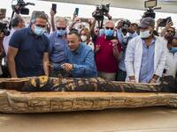 A picture taken on October 3, 2020 shows Egyptian Minister of Tourism and Antiquities Khaled Al-Anani (L), and Mustafa Waziri (R), Secretary General of the Supreme Council of Antiquities, unveil the mummy inside a sarcophagus excavated by the Egyptian archaeological mission working at the Saqqara necropolis, 30 kms south of the capital Cairo, which resulted in the discovery of a deep burial well with more than 59 human coffins closed for more than 2,500 years. They were unearthed south of Cairo in the spraw