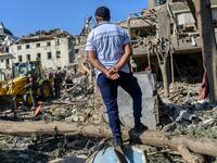A man looks at rescuers searching for victims or survivors at the blast site hit by a rocket during the fighting between Armenia and Azerbaijan over the breakaway region of Nagorno-Karabakh, in the city of Ganja, Azerbaijan, on October 11, 2020. Bulent Kilic / AFP