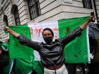 A protester holds a flag stained with fake blood during a demonstration outside the Nigerian High Commission against police brutality in Lagos in London on October 21, 2020. UN Secretary General Antonio Guterres called Wednesday for an end to what he called "brutality" by police in Nigeria, which has been rocked by two weeks of protests. Guterres said gunmen that opened fire on peaceful protesters Tuesday evening in Lagos caused "multiple deaths" and many injuries. Daniel LEAL-OLIVAS / AFP