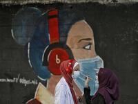 Palestinian students interact as they paint murals of a mask-clad girls in Gaza City on October 22, 2020, amid the novel coronavirus pandemic crises. Mohammed ABED / AFP