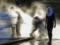 Demonstrators clash with riot police during a protest against Chilean President Sebastian Pinera's government on the constitutional referendum voting day at Plaza Italia square in Santiago on October 25, 2020. A year to the day after more than one million people thronged downtown Santiago in the biggest Chile's social uprising, Chileans vote Sunday on whether to change the country's dictatorship-era constitution seen as underpinning the nation's glaring inequalities. MARTIN BERNETTI / AFP