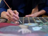 This photograph taken on October 8, 2020 shows 89-year-old Vietnamese artist Mong Bich painting at her house in Bac Ninh province, east of Hanoi. Bich specialises in silk paintings of daily life and ordinary people, women in particular, and ploughed a lonely furrow during many years of war when artists were steered towards the army or frontline workers as subjects. Manan VATSYAYANA / AFP