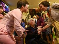 This photograph taken on October 22, 2020 shows guests greeting 89-year-old Vietnamese artist Mong Bich during the opening of her first solo exhibition at the French Cultural Centre in Hanoi. Bich specialises in silk paintings of daily life and ordinary people, women in particular, and ploughed a lonely furrow during many years of war when artists were steered towards the army or frontline workers as subjects. Manan VATSYAYANA / AFP