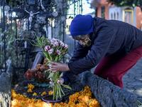 A woman decorates a relative's grave at La Magdalena Pantheon, in San Pedro Cholula, Puebla state, Mexico, on November 1, 2020, on All Saints' Day, amid the COVID-19 coronavirus pandemic. Local authorities have restricted the visit times and the number of visitors in cemeteries due to the pandemic. PEDRO PARDO / AFP