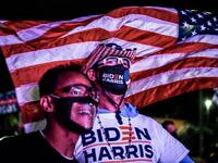 Alex Suarez (L) and Ralph Reichard (R) supporters of the Democratic party cheer as they attend a watch party in Miami, Florida on November 3, 2020. The US is voting Tuesday in an election amounting to a referendum on Donald Trump's uniquely brash and bruising presidency, which Democratic opponent and frontrunner Joe Biden urged Americans to end to restore "our democracy." CHANDAN KHANNA / AFP