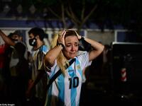 A woman wearing an Argentina number 10 shirt holds her head in grief as she gathers with other fans to pay tribute in Buenos Aires' La Paternal neighbourhood. (AFP/File)