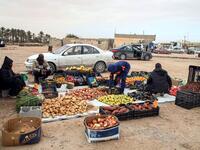 Produce vendors sit by their fruit and vegetable merchandise in the open in the city of Tawergha, some 200 kilometres (125 miles) east of Libya's capital close to the port city of Misrata, on December 12, 2020. When Libyan dictator Moamer Kadhafi was toppled, people took revenge on those they saw as his supporters -- including the entire town of Tawergha, whose 40,000 residents were forced to flee. Now, almost a decade later since militia forces rampaged through the town torching homes, destroying buildings