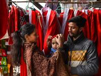 In this picture taken on December 15, 2020, a Christian family buys a Santa Claus outfit for their son at a shop ahead of Christmas celebrations in Lahore. Arif ALI / AFP