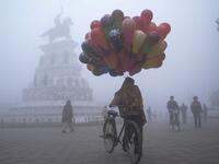 A balloon seller walks along Heritage street amid dense fog on a cold day on New Year's Day, in Amritsar on January 1, 2021. NARINDER NANU / AFP