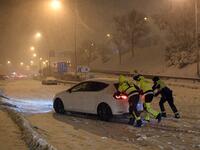 Firefighters push a vehicle stuck in the M30 ringroad in Madrid due to a heavy snow storm on January 8, 2021. Heavy snow fell across much of Spain today, leaving huge areas blanketed in white as Storm Filomena brought wintry weather not seen in decades to the Iberian peninsula. The intense snow cut off Madrid's two ringroads, the M30 and the M40, and a red alert was declared in the city centre where police were struggling to help people stranded in vehicles. OSCAR DEL POZO / AFP