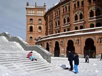 A woman slides down steps outside the Las Ventas bullring in Madrid on January 10, 2021. Snowstorms in Spain left three people dead and caused chaos across much of the country, trapping motorists and shutting down the capital's air and rail links. Gabriel BOUYS / AFP