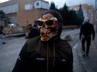 A Lebanese anti-government protester wears a mask during clashes with security forces in front of the Serail (headquarters of the Governorate), in the northern port city of Tripoli, following a demonstration to protest against the economic situation, on January 28, 2021. Tripoli was already one of Lebanon's poorest areas before the coronavirus pandemic piled new misery onto a chronic economic crisis. Many of its residents have been left without an income since Lebanon imposed a full lockdown earlier this mo