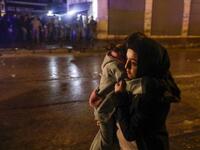 A woman crosses a street with her child during clashes between security forces and anti-government protesters in the northern city of Tripoli, on January 29, 2021. More than 400 people have been wounded in northern Lebanon this week in clashes between security forces and protesters angered by a coronavirus lockdown they say is starving them. JOSEPH EID / AFP