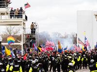 Pro-Trump protesters stand on a media platform in front of a line of police officers after breaking through barriers onto the grounds of the Capitol Building on January 6, 2021 in Washington, DC. A pro-Trump mob stormed the Capitol earlier, breaking windows and clashing with police officers. Trump supporters gathered in the nation's capital to protest the ratification of President-elect Joe Biden's Electoral College victory over President Donald Trump in the 2020 election. Jon Cherry/Getty Images/AFP