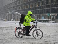 A person on a delivery bike rides during a winter storm on February 1, 2021 in New York City. A powerful winter storm is set to dump feet of snow along a stretch of the US east coast including New York City on February 1, 2021, after blanketing the nation's capital. The National Weather Service issued storm warnings from Virginia to Maine -- a swathe home to tens of millions of people -- and forecast snowfall of 18 to 24 inches (45-60 centimeters) in southern New York, northeastern New Jersey and parts of s