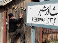 In this picture taken on February 9, 2021, street actor Usman Khan, dressed up as silent film star Charlie Chaplin, performs in the Pakistan's northwestern city of Peshawar. Wearing a bowler hat and familiar toothbrush moustache, Pakistan's Usman Khan darts through traffic swinging a cane, teasing motorists and shopkeepers for laughs and a few rupees with a Charlie Chaplin impersonation that has become a viral sensation.  Abdul MAJEED / AFP