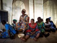 A group of gold miners site on the floor in the backstage after having been selected by the Princess of Burundi, Esther Kamatari, to take part in a fashion show as part of the first edition of the International Gold Fair Afrik'Or, in Bamako, on February 12, 2021. The Princess of Burundi, selected 34 women among gold mines workers in southern Mali, to walk down the catwalk for a fashion show organised during the International Gold Fair. Gold represents 15% of Mali's exports and more than 20% of its GDP estim