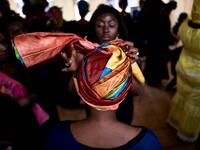 A dresser helps a gold miner to wear a turban in the backstage prior to take part in a fashion show as part of the first edition of the International Gold Fair Afrik'Or, in Bamako, on February 12, 2021. The Princess of Burundi Esther Kamatari, selected 34 women among gold mines workers in southern Mali, to walk down the catwalk for a fashion show organised during the International Gold Fair. Gold represents 15% of Mali's exports and more than 20% of its GDP estimated at nearly US$20 billion by the end of 20