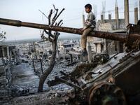  Syrian Kurdish boy sits on a destroyed tank in the Syrian town of Kobane