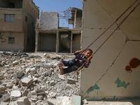  Syrian boy plays on a swing in a destroyed building