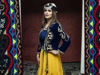 A Syrian Kurdish woman in traditional attire poses for a picture 