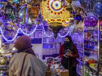 Women talk to a Palestinian shopkeeper selling Ramadan lanterns 