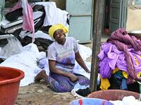 A dyer smiles as she poses for a photograph at Pathe'O house in the popular district of Treichville in Abidjan on March 31, 2021. A small self-taught tailor in his early years, the Ivorian-Burkinabe Pathe'O became the designer of African heads of state and celebrates the fiftieth anniversary of his brand, leading the "fight" for the recognition of fashion on the continent