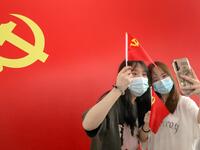 Passengers take photos with a flag of the Communist Party of China at the Nantong Railway Station in China's eastern Jiangsu province on July 1, 2021, during celebrations to mark the 100th anniversary of the founding of the Communist Party of China