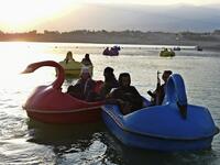 In this photograph taken on September 28, 2021 Taliban fighters ride on paddle boats at Qargha Lake on the outskirts of Kabul. "This is Afghanistan!" a Taliban fighter shouts on the pirate ship ride at a fairground in western Kabul, as his armed comrades cackle and whoop on board the rickety attraction. (Photo by WAKIL KOHSAR / AFP) / TO GO WITH: AFGHANISTAN-CONFLICT-FAIRGROUND, SCENE BY JAMES EDGAR - TO GO WITH: Afghanistan-conflict-fairground, SCENE by James EDGAR