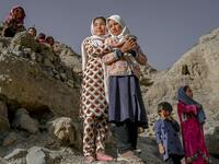 In this picture taken on October 3, 2021, Hazara ethnic people stand on a cliff pockmarked by caves where people still live as they did centuries ago in Bamiyan. 
