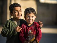 طفلان فلسطينيان يبتسمان داخل مخيم للنازحين في خان يونس جنوب قطاع غزة خلال تجمع لمتابعة مباراة في كأس العالم 2026.