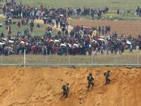 A picture taken on March 30, 2018 from the southern Israeli kibbutz of Nahal Oz across the border from the Gaza strip shows Palestinians participating in a tent city protest commemorating Land Day, with Israeli soldiers seen below in the foreground. 
(Jack GUEZ / AFP)