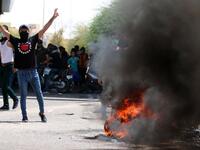 An Iraqi protester gestures near a burning tyre during a demonstration in Basra on July 15, 2018. (AFP/Haidar Mohammad Ali)