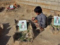 A Yemeni child recites a prayer by the graves of schoolboys who were killed while on a bus that was hit by a Saudi-led coalition air strike on the Dahyan market in August, at a cemetery in the Huthi rebels' stronghold province of Saada on September 4, 2018. 
STRINGER / AFP