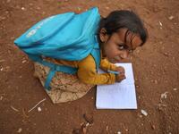 A Syrian child who fled with her family from the northern countryside of Hama, writes in a notebook in the yard of the makeshift school of "Zuhur al-Mustaqbal" (in Arabic "Flowers of the Future") in al-Jeneinah camp Aaref WATAD / AFP