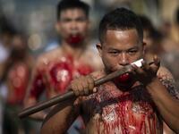 A devotee of the Loem Hu Thai Su shrine cuts his tongue on an axe as he parades during the annual Vegetarian Festival in Phuket on October 12, 2018. Jewel SAMAD/AFP